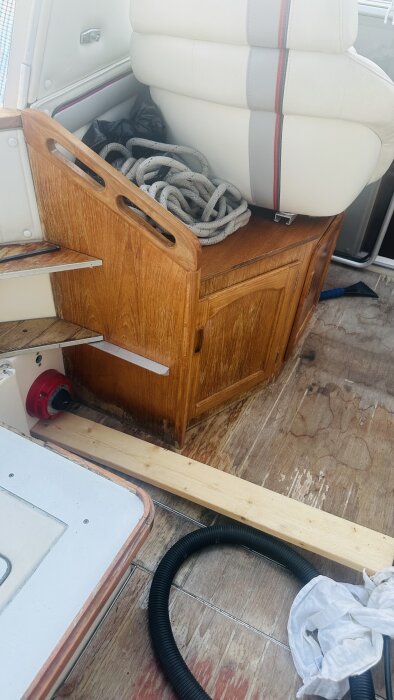 Del av äldre, sliten båtinredning med träskåp och sittbrunnsdurk som behöver renoveras.