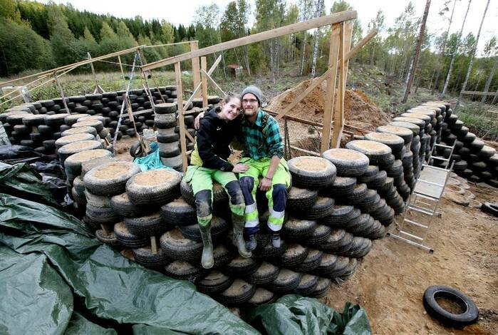 Två personer sitter på en stapel däck vid en byggplats för ett jordskepp.