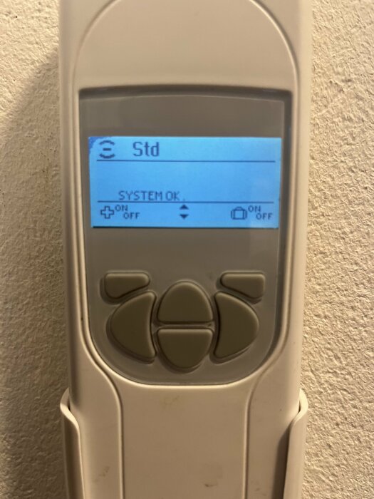 Fjärrkontroll för FTX-system med displayen visande "Std" och "SYSTEM OK".