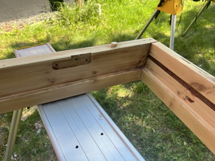 Slipad träkarm med utspacklade hål och synliga spår på sidostyckena placerad på en arbetsbänk utomhus.