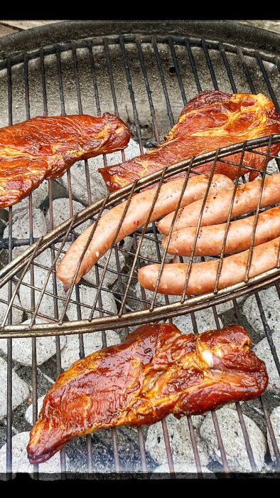 Grillat kött och korvar på en grillgrate över glödande kol.