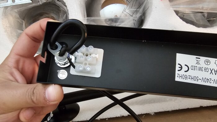 Taklampans monteringsplatta med en icke ansluten elektrisk kontakt och en ansluten tråd.