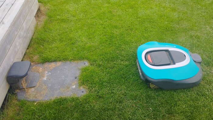 Robotgräsklippare R100Li nära laddstationen på en gräsmatta.
