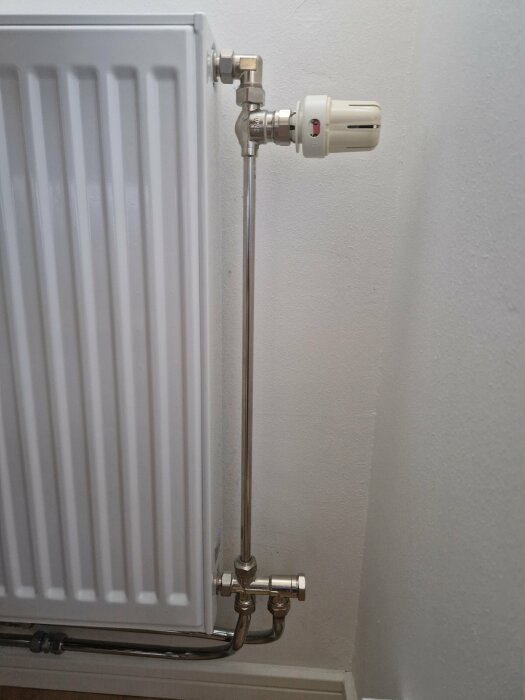 Radiator med termostatventil och synligt radiatorkoppel samt täcklock för avstängning.