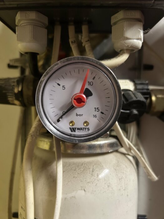 Manometer på solfångarsystem visar 0 bar tryck, anslutna rör och del av expansionskärl syns.