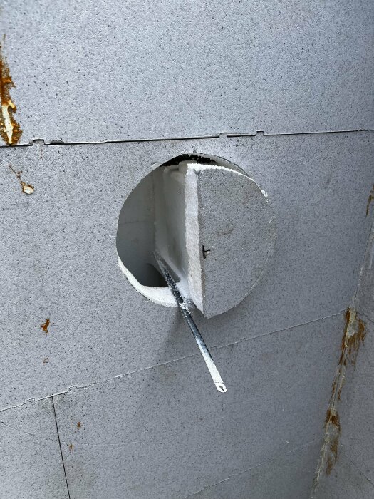 Infästningsdetalj för lamelltäcke installerad i grå betongvägg med rund utskärning.