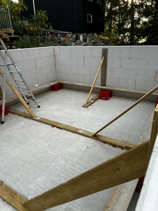 Förberedelse av betonggjutning med stödstag och kontreforer i en grå lecablockkonstruktion.
