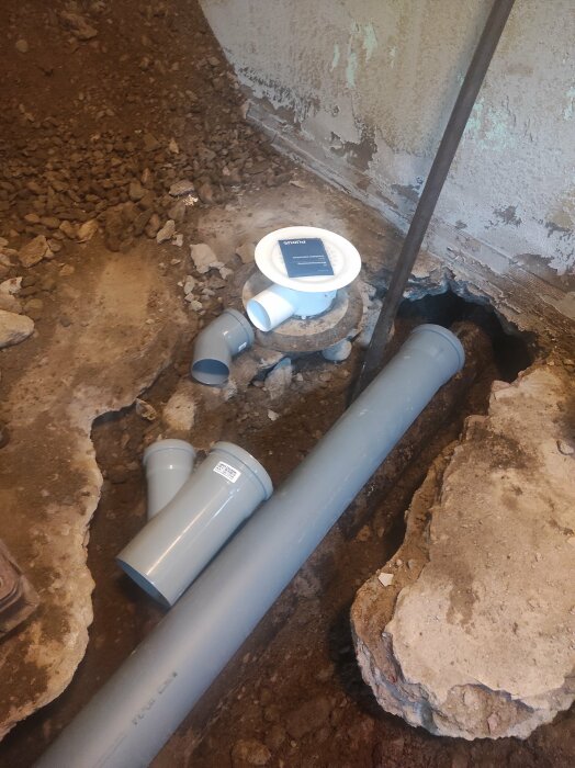 Renovering av tvättstugans avloppssystem med nya rör och kopplingar i en grovgrävd källare.