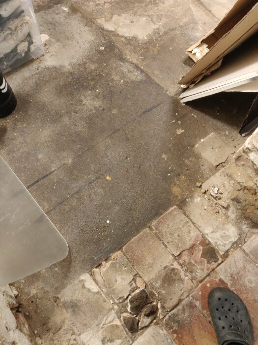 Delvis teglat golv med fuktfläckar i en källare från 1900-tals villa.