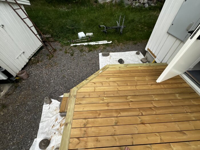 Nylagd trätrall på en terass med anslutning till en annan terass, verktyg syns i bakgrunden.