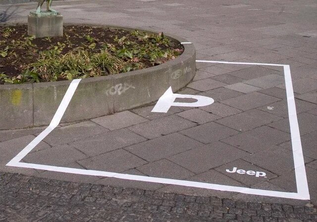 Parkering för Jeep markerad på trottoar intill plantering med vit linje och bokstaven 'P'.