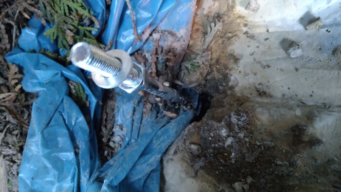 Bult och mutter som fyller ut glappet runt stänger med geggamoja och underliggande plast.