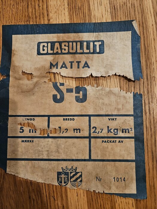 Nött etikett för GLASULLIT matta, 5 m längd, 1,2 m bredd och 2,7 kg/m2 vikt, med logotyper.