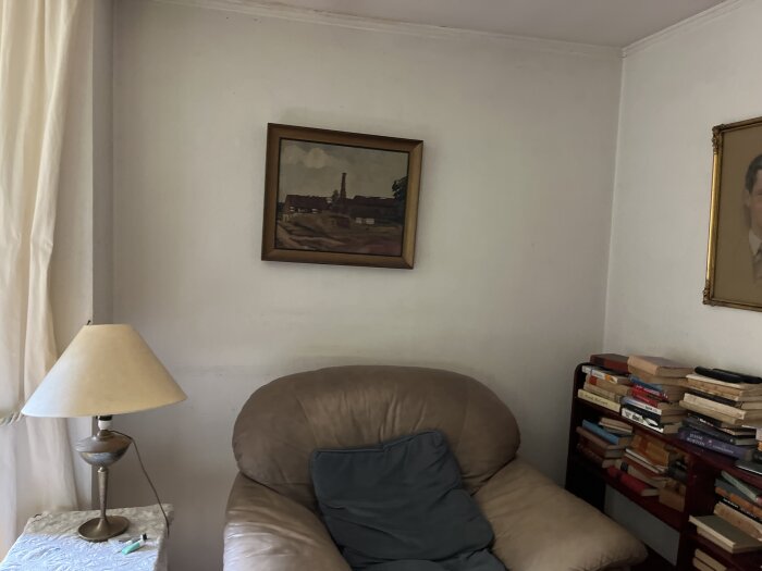 Hörn av ett vardagsrum med slitna vita väggar och tak, bruna bokhyllor, och en brun fåtölj.