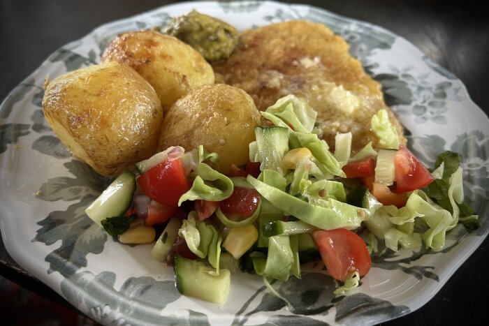 En tallrik med schnitzel, ugnstekt potatis med vitlökssmör, blandad sallad, och klick guacamole.