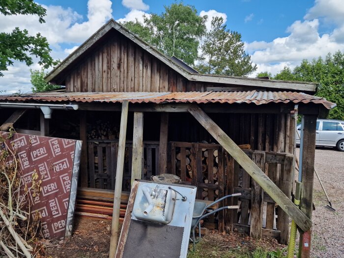 Förfallet 40-talsgarage med plåttak och brädfasader som används som förråd och verkstad.