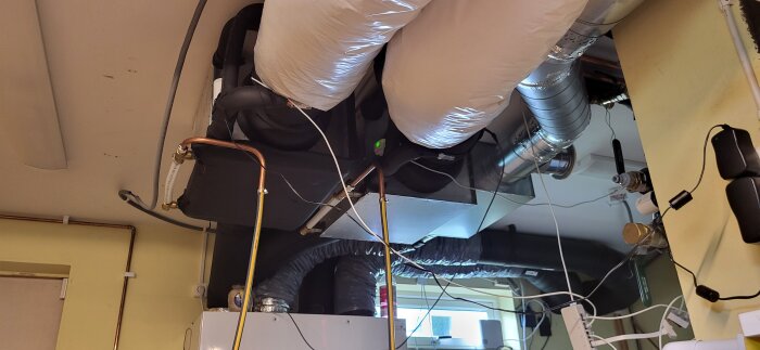 Installation av HVAC-system med synliga rör och isolering i ett teknikrum.