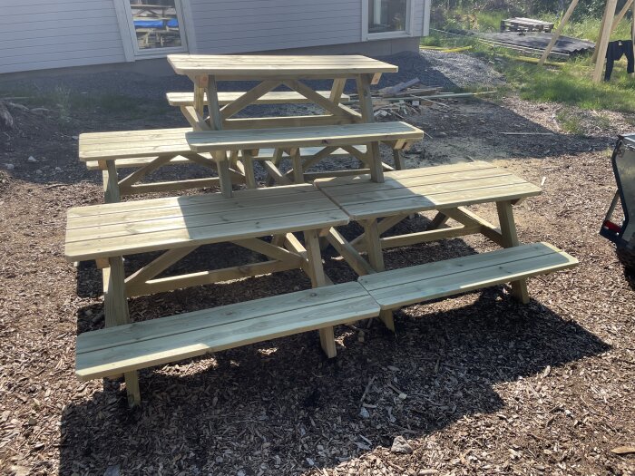 Två nya träpicknickbord framför en byggarbetsplats för massproduktion till förskola.