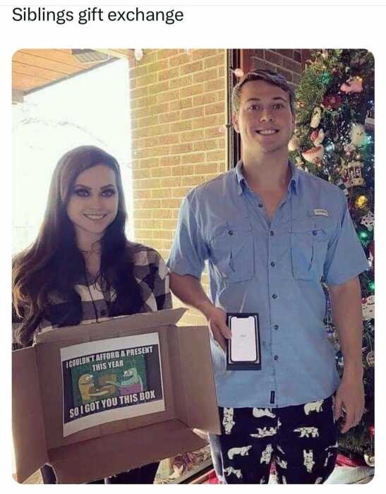 Kvinnan och mannen ler med julklappsutbyte, mannen håller en tom ask med texten "I couldn't afford a present this year so I got you this box".