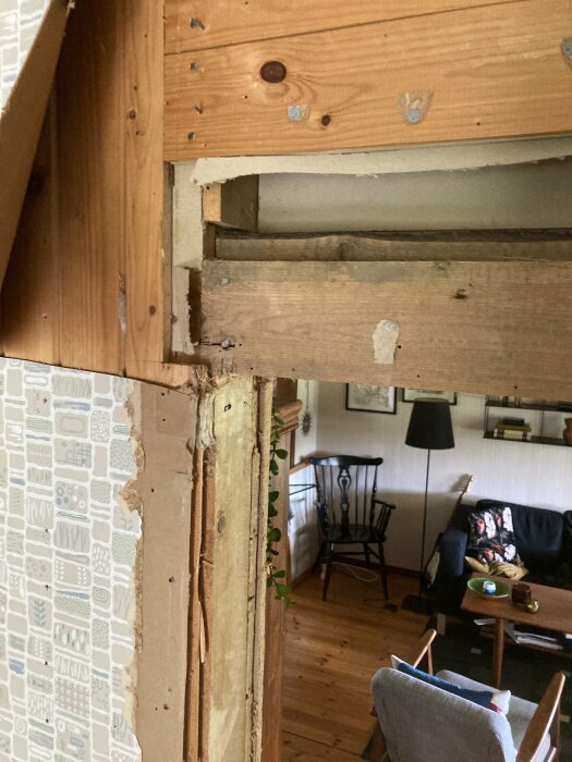 Delvis rivna väggar i ett rum som visar reglar och plankor nära ett dörrhål.