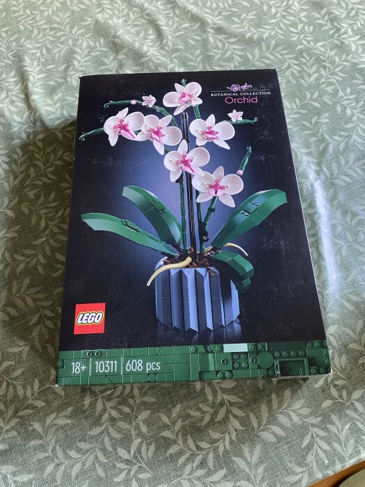 LEGO Botanical Collection Orchid set lådan på ett mönstrat tyg.