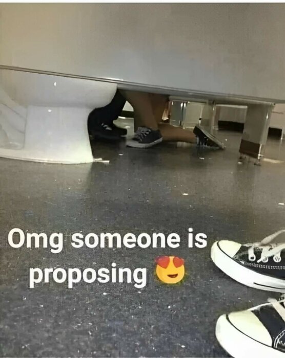 Två personer under ett bås, en på knä som om de friar, med överlagrad text "Omg someone is proposing 😍".