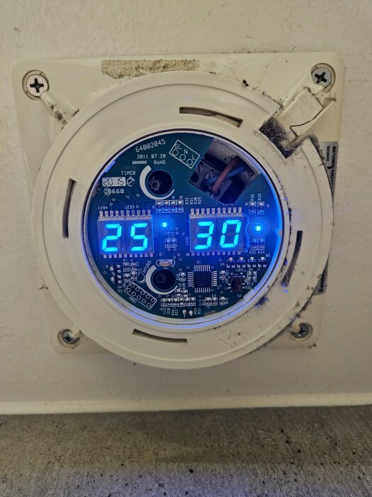 Söndrig Cata badrumsfläkt utan glasfront, exponerade elektroniska komponenter och LED-display visar 25 och 30.