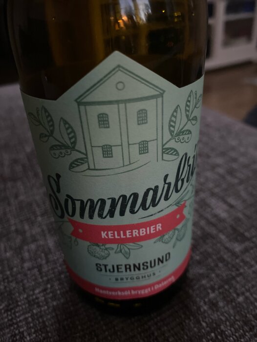 Flaska med etikett 'Sommarbris Kellerbier' från Stjernsund Brygghus, illustration av hus och blad.