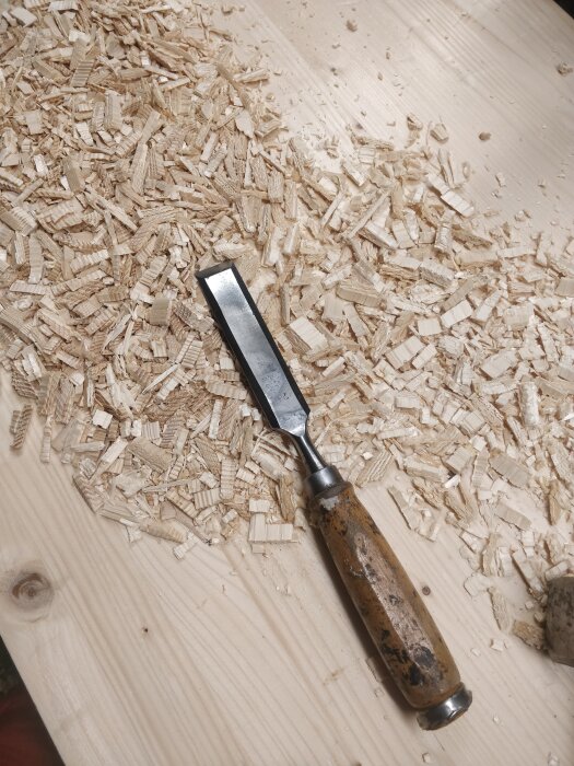 En hyvel ligger på ett bord med spån som resultat av träbearbetning.