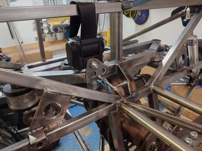 Bromsslangsfäste och bältesspänne på en byggd metallram som förstärkning i ett fordonschassi.
