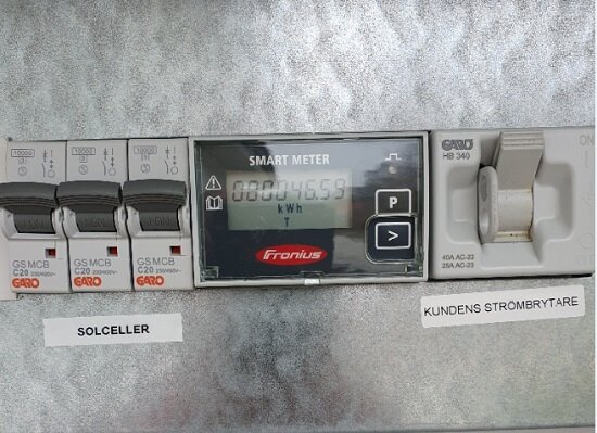Tre separata 20A automatsäkringar bredvid en Fronius Smart Meter och en kundens strömbrytare med etiketter för solceller.