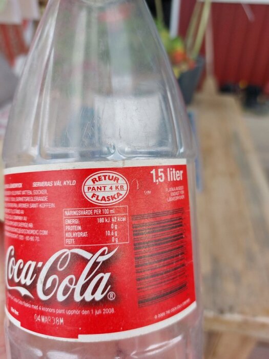 Tom Coca-Cola flaska på 1,5 liter med etikett och texten "RETUR PANT 4 KR FLASKA" framträdande.