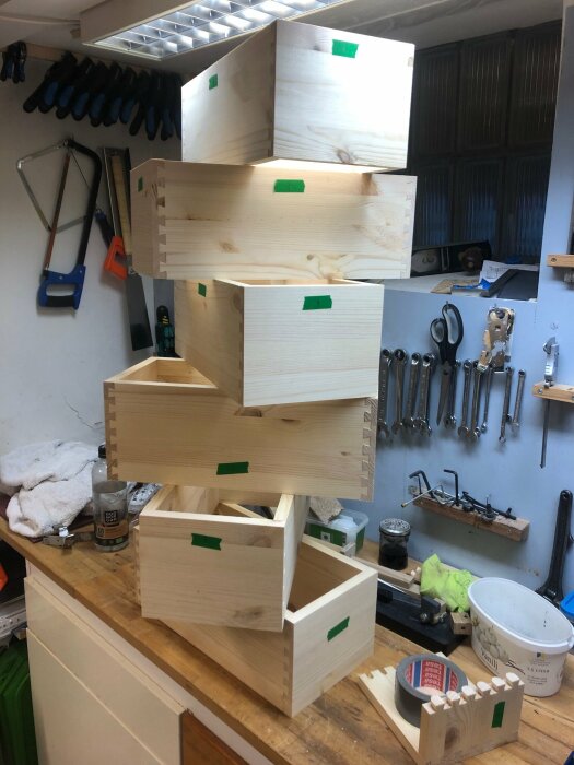 Hantverksmässiga trä lådor i olika storlekar med fingerskarvar på en verkstadsbänk.