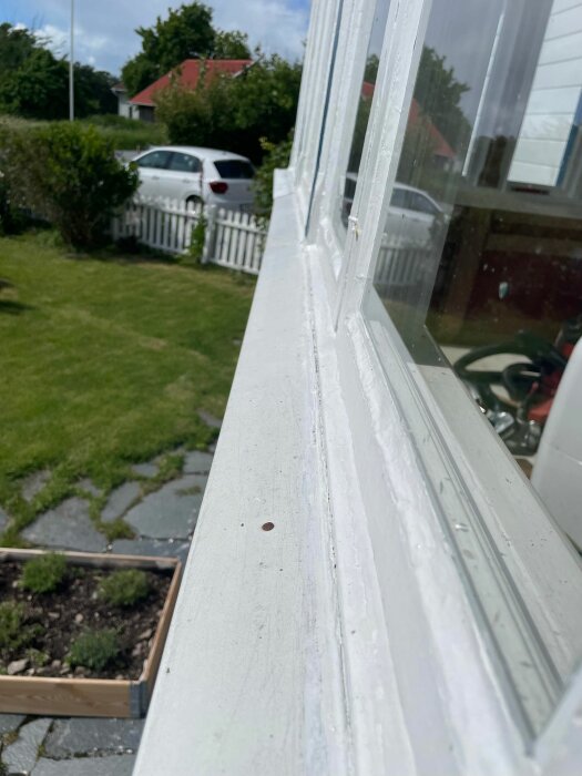 Vit verandafönsterkarm med bristande anslutning till blecket, möjliga vattenskador synliga.