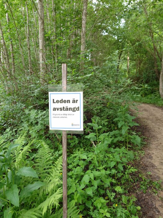 Skogsstig med skylt som lyder "Leden är avstängd" på grund av dåligt skick.