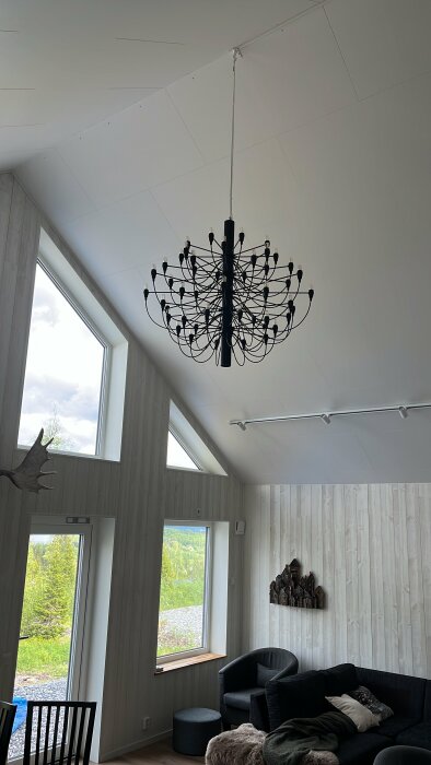 Hemmagjord kopia av Sarfatti-lampkrona med 50 ljuskällor hängandes i ett rum med högt i tak.