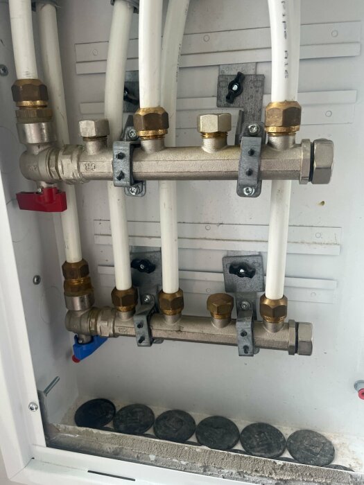 VVS-installation i badrum med svårvridna blå och röda ventiler på ett rörsystem.