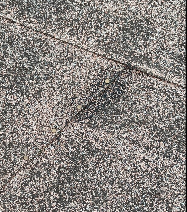 Närbild på ett papptak med synliga spikar längs skarvar mellan takpappblad.