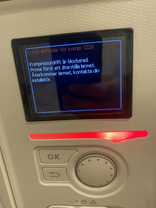 Display på Nibe f730 visar ett larm med texten: "Korta drifttider för kompr. (229) Kompressordrift är blockerad. Prova först att återställa larmet.