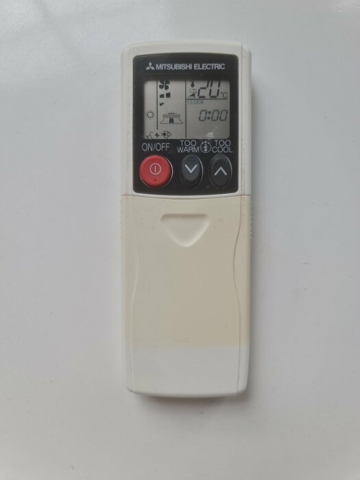 Fjärrkontroll till en Mitsubishi Electric luftvärmepump med en digital display som visar 20 grader Celsius och flera knappar för funktioner som på/av-knapp.