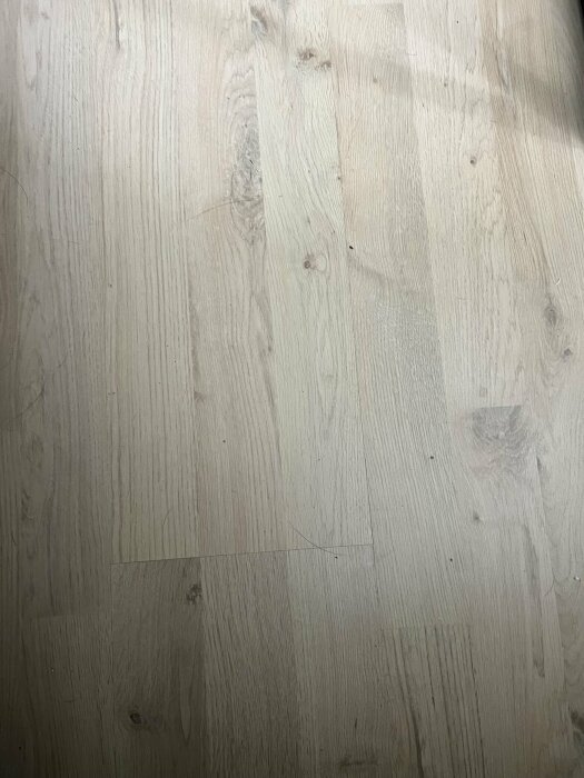 Ljusa laminatgolvplankor med trästruktur och knastar, som diskuteras för användning på trappsteg.