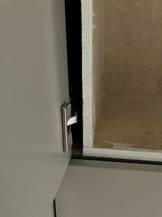 Bild av ett skåp med en öppen lucka som visar ett mellanrum mellan dörren och en hylla på insidan, med gångjärnet tydligt synligt vid kanten.