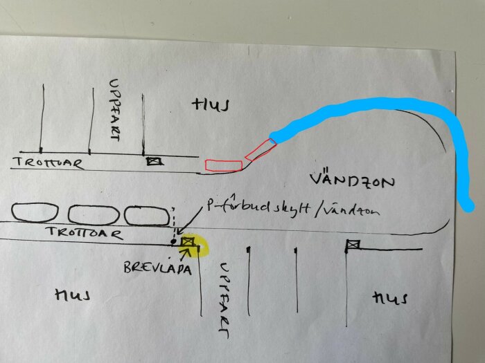 Handritad karta över en bostadsområde med vägar och trottoarer, visar förslag på samlad plats markerad i gult.