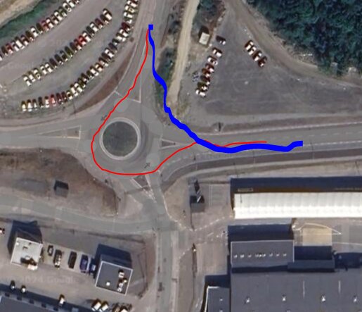 Flygfoto av rondell med huvudväg markerad i rött och föreslagen rakare väg markerad i blått, föreslagen att minska trafikköer och bränsleförbrukning.