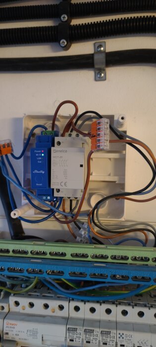Elinstallation med kopplingsschema, där en kopplingsenhet av märket Shelly är synlig, tillsammans med flera elkablar och kopplingsplintar.