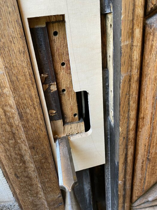 Träbearbetning av dörrkarm med hjälp av en trämall och ett stämjärn för förberedning av gångjärnsbyte på en gammal dörr från tidigt 1900-tal.
