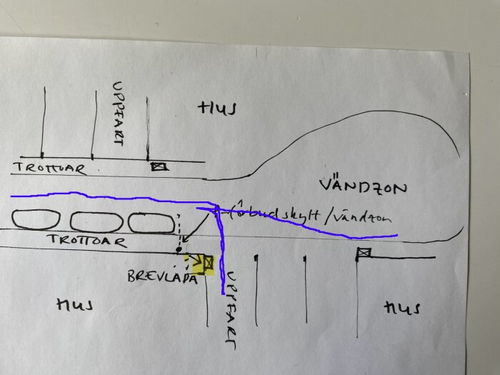 Handritad karta som visar trottoarer, uppfarter, vändzon, brevlåda och förbudsskylt/vändzon markerat med blått. Brevlådan föreslås flyttas närmare uppfarten.