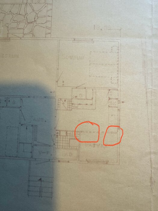 Ritning av ett hus med två områden markerade med röda cirklar som indikerar en vägg mellan kök och matplats.