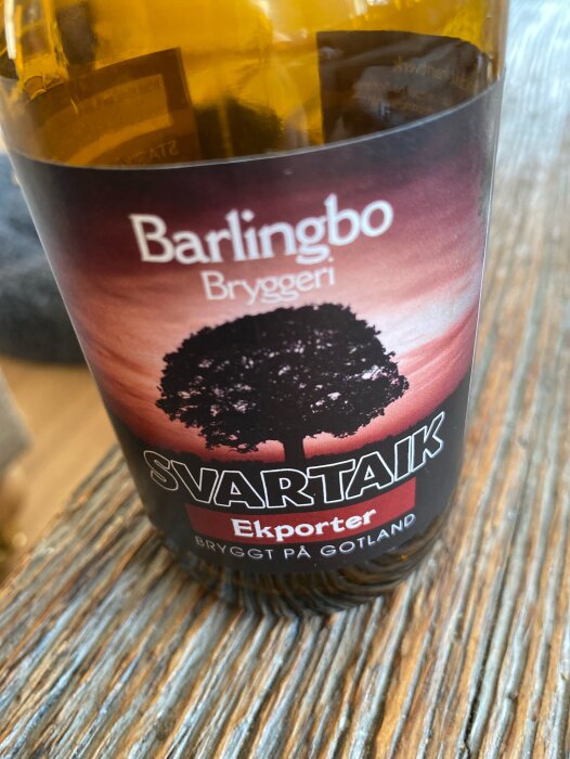 En flaska med etiketten "Barlingbo Bryggeri Svartaik Ekporter Bryggt på Gotland" på ett träbord.