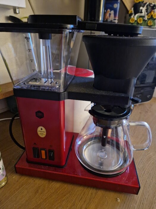 Röd OBH Nordica kaffebryggare med glasbehållare, står på en köksbänk.